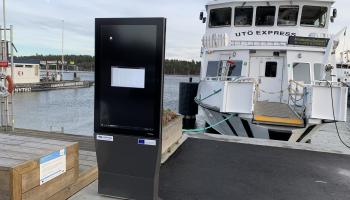 Digital info screen on a pier in front of an archipelago ferry